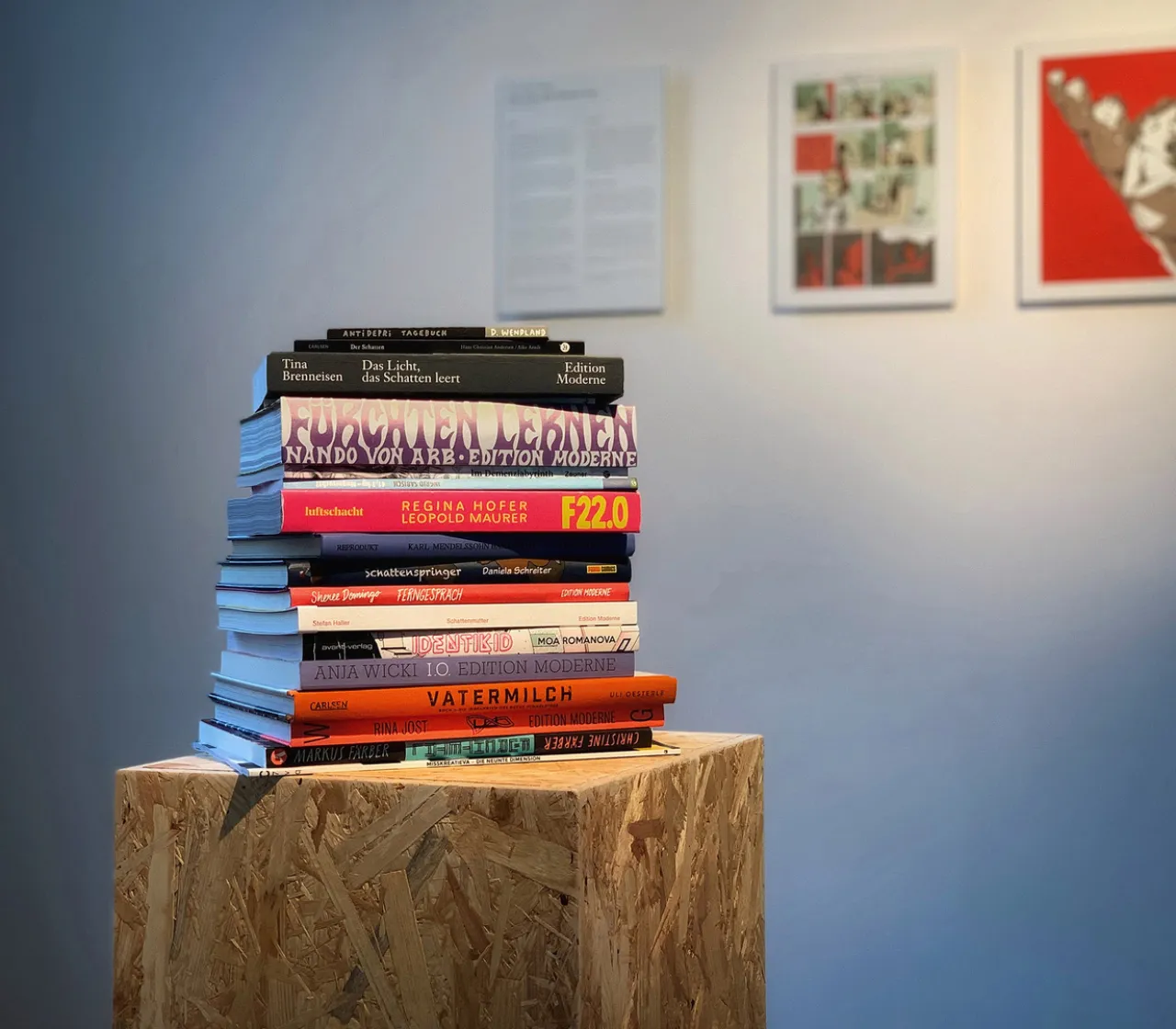 20 Bücher auf einem Stapel auf einem Holzblock im Ausstellungsraum
